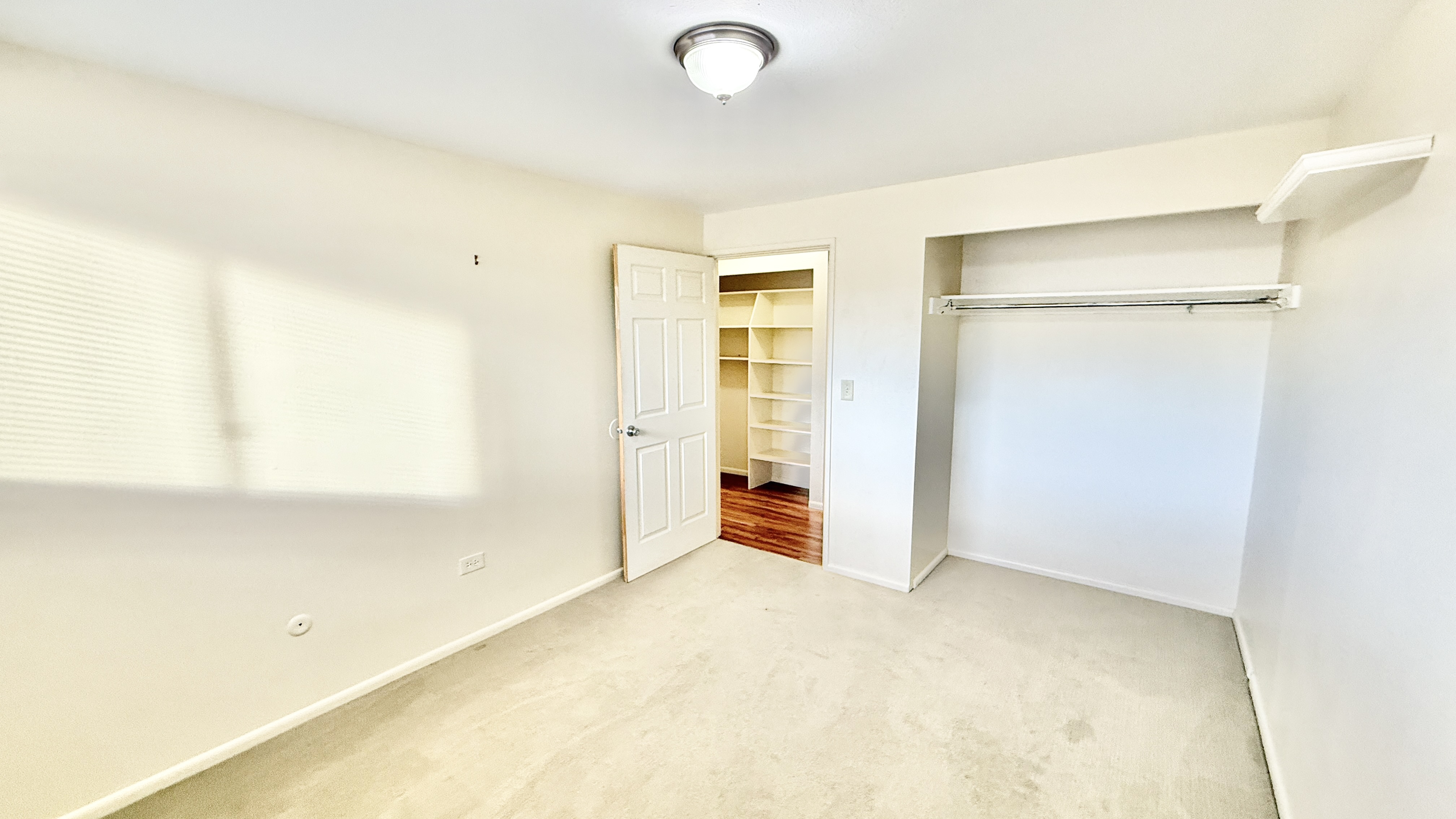 Bright and spacious bedroom with plush carpeting and a walk-in closet, showcasing a tranquil and modern living space.
