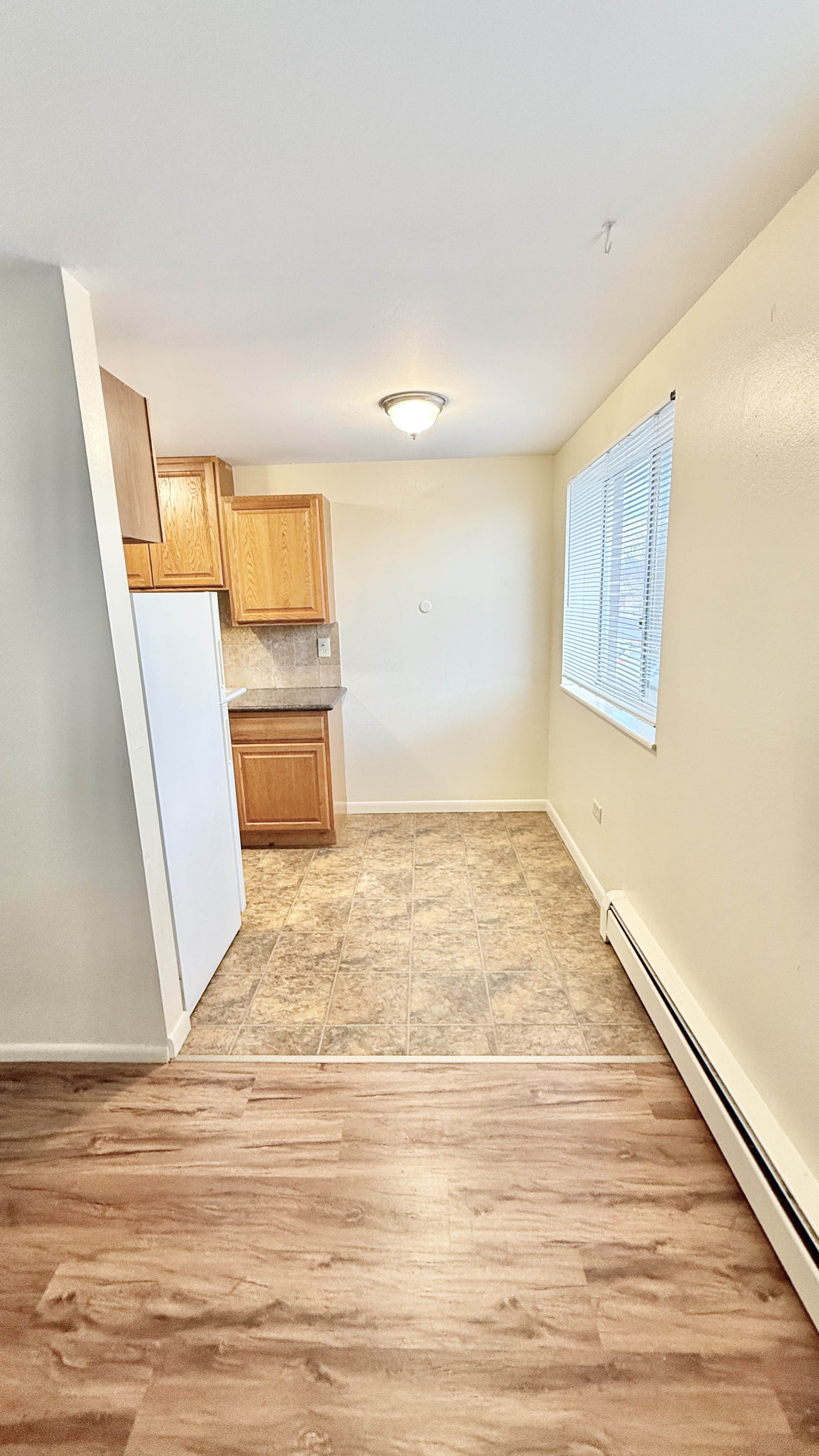 Bright and cozy kitchen space featuring light wood cabinetry, tile flooring, and natural light from a large window.