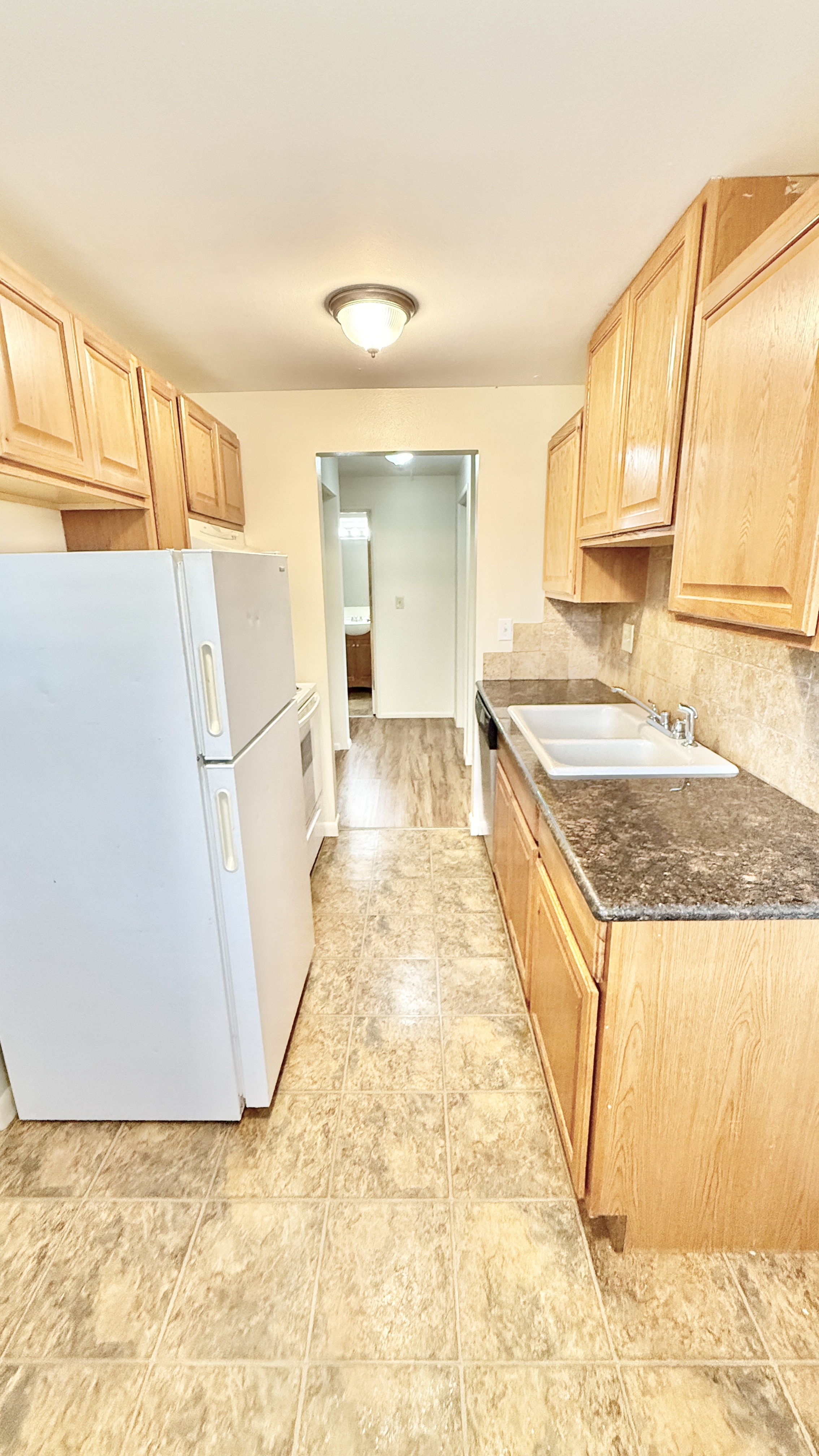 Bright and inviting galley kitchen with modern countertops and ample wooden cabinetry.