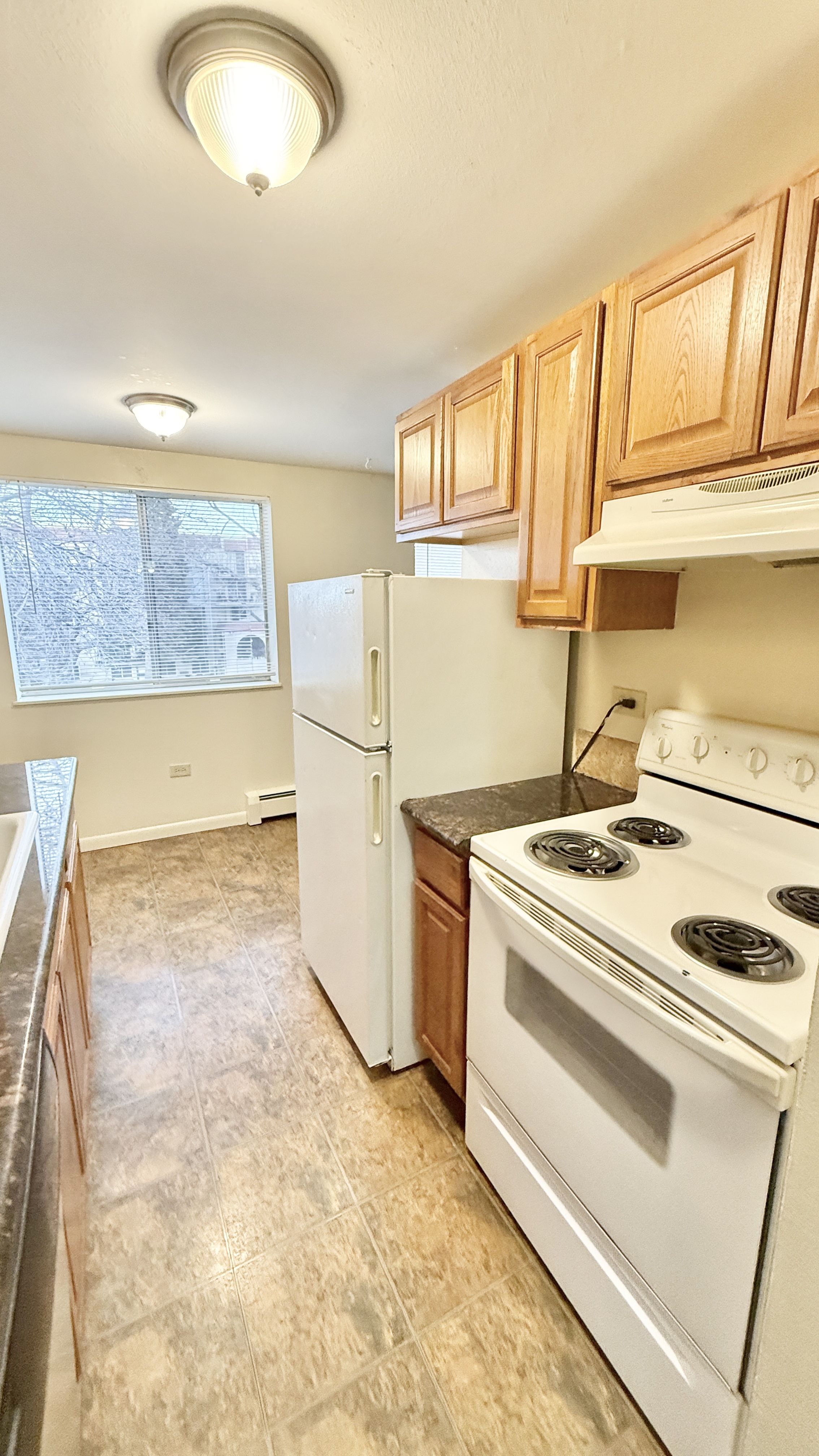 Bright kitchen with modern appliances, ample wooden cabinetry, and a large window offering a pleasant view, ideal for culinary creativity and comfort.
