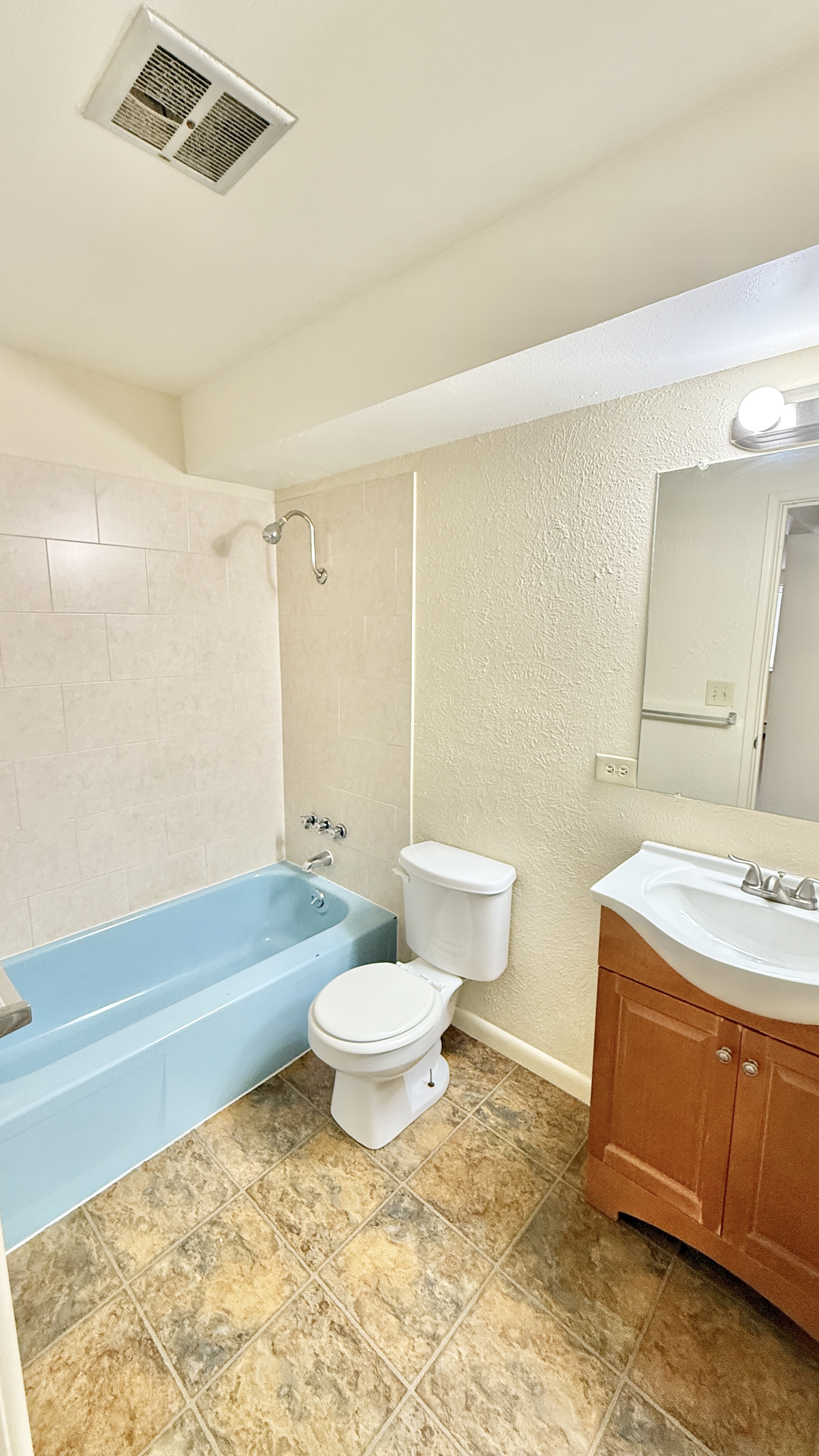 Bright, clean bathroom featuring a stylish blue bathtub, modern vanity, and elegant tile flooring.