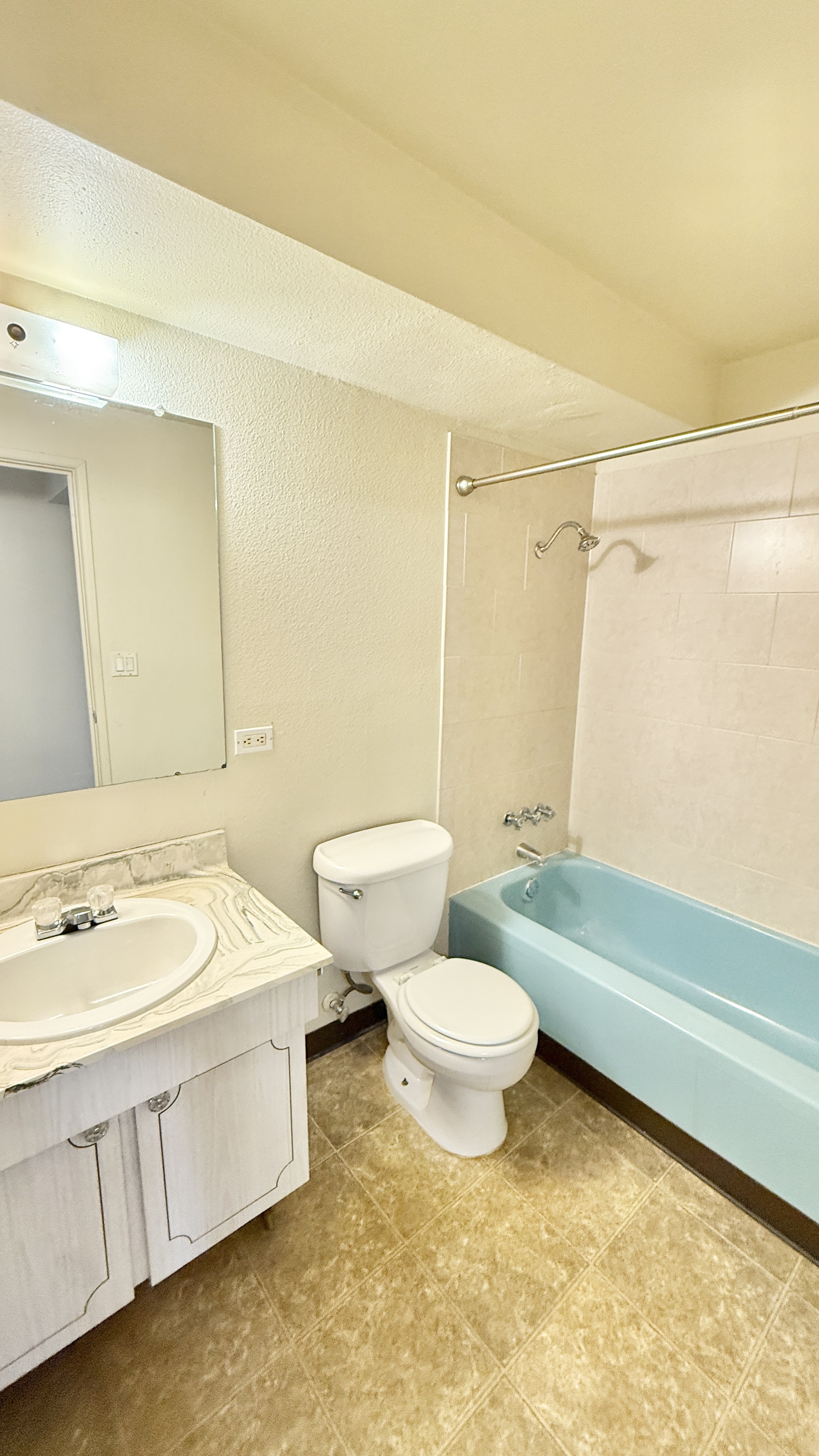 Bright and inviting bathroom featuring a sleek blue bathtub, modern sink with marble countertop, and stylish tile flooring.