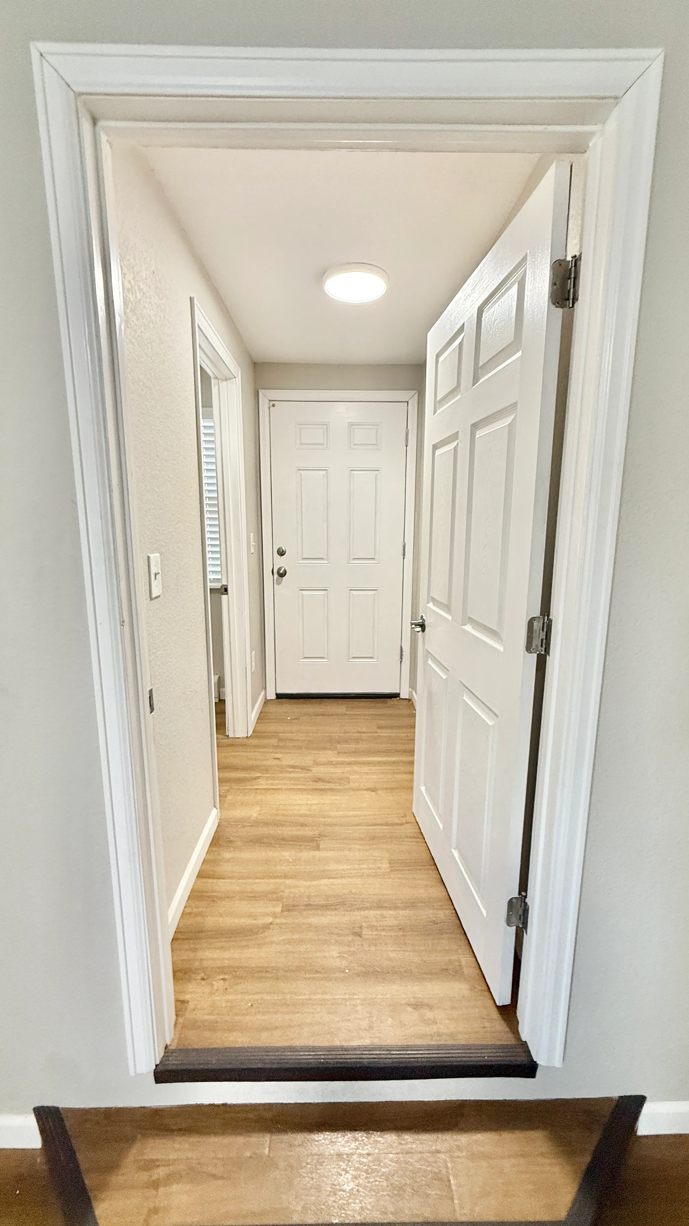 Bright entryway with modern white doors, wooden flooring, and natural light enhancing the welcoming ambiance.