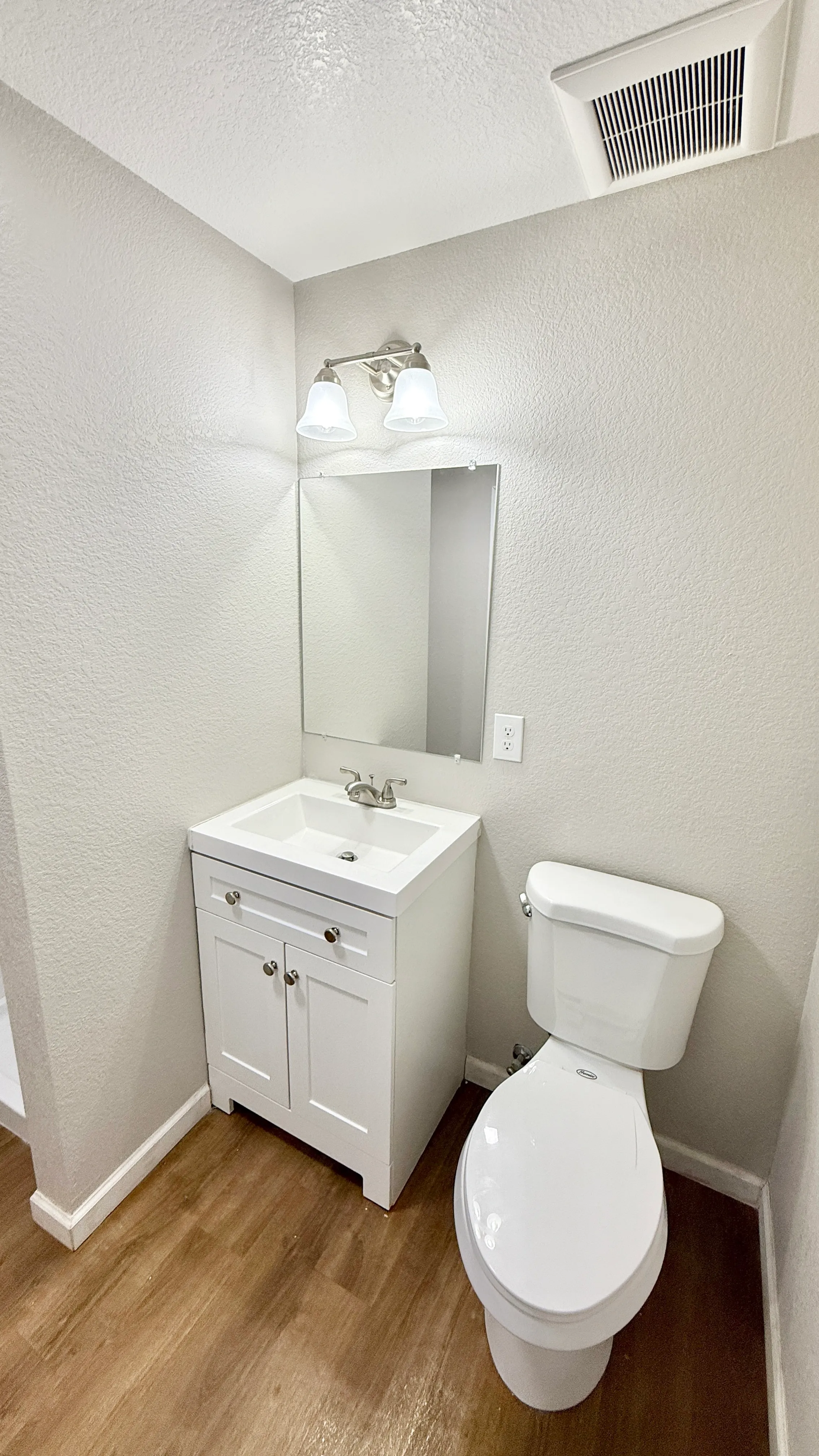 Elegant bathroom with modern fixtures, featuring a sleek white vanity, stylish wall mirror, and contemporary lighting.