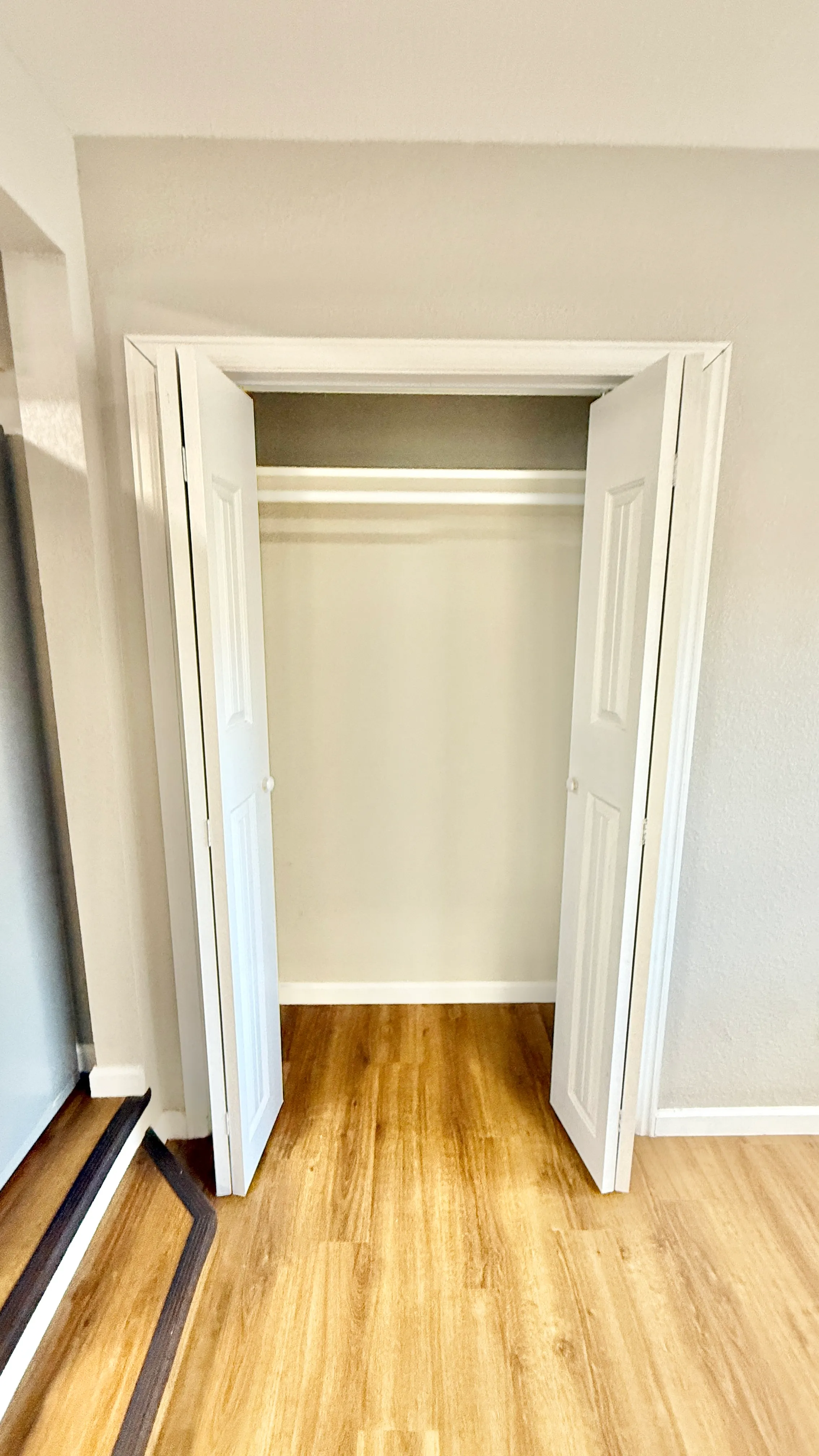 Bright, open closet with bi-fold doors, showcasing elegant wood flooring and a modern design.