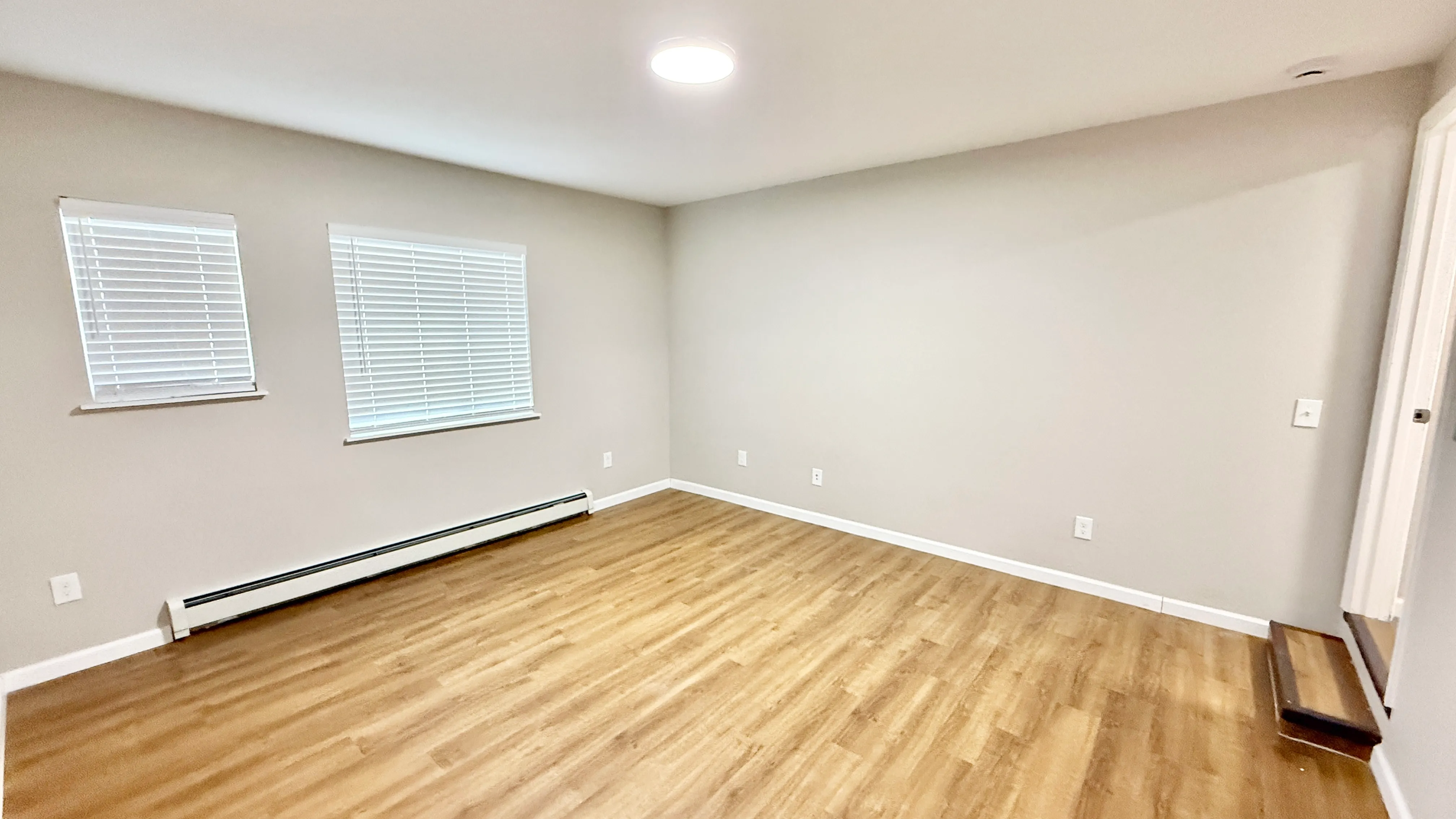 Bright and spacious room with elegant wood flooring, large windows, and natural light, ideal for a cozy living area or home office.