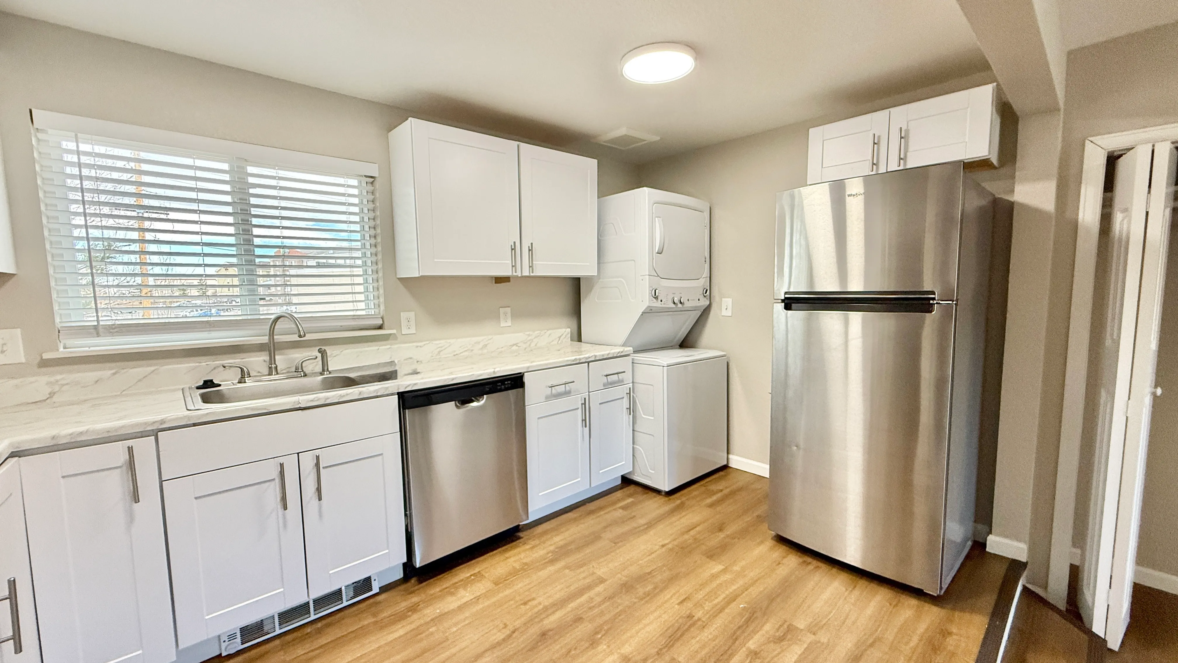 Bright modern kitchen featuring sleek stainless steel appliances, white cabinetry, and in-unit washer and dryer for convenience.