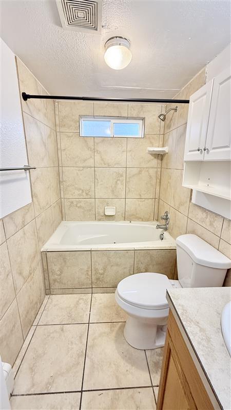 Bright bathroom featuring a soaking tub, tile accents, and ample storage for a modern living experience.