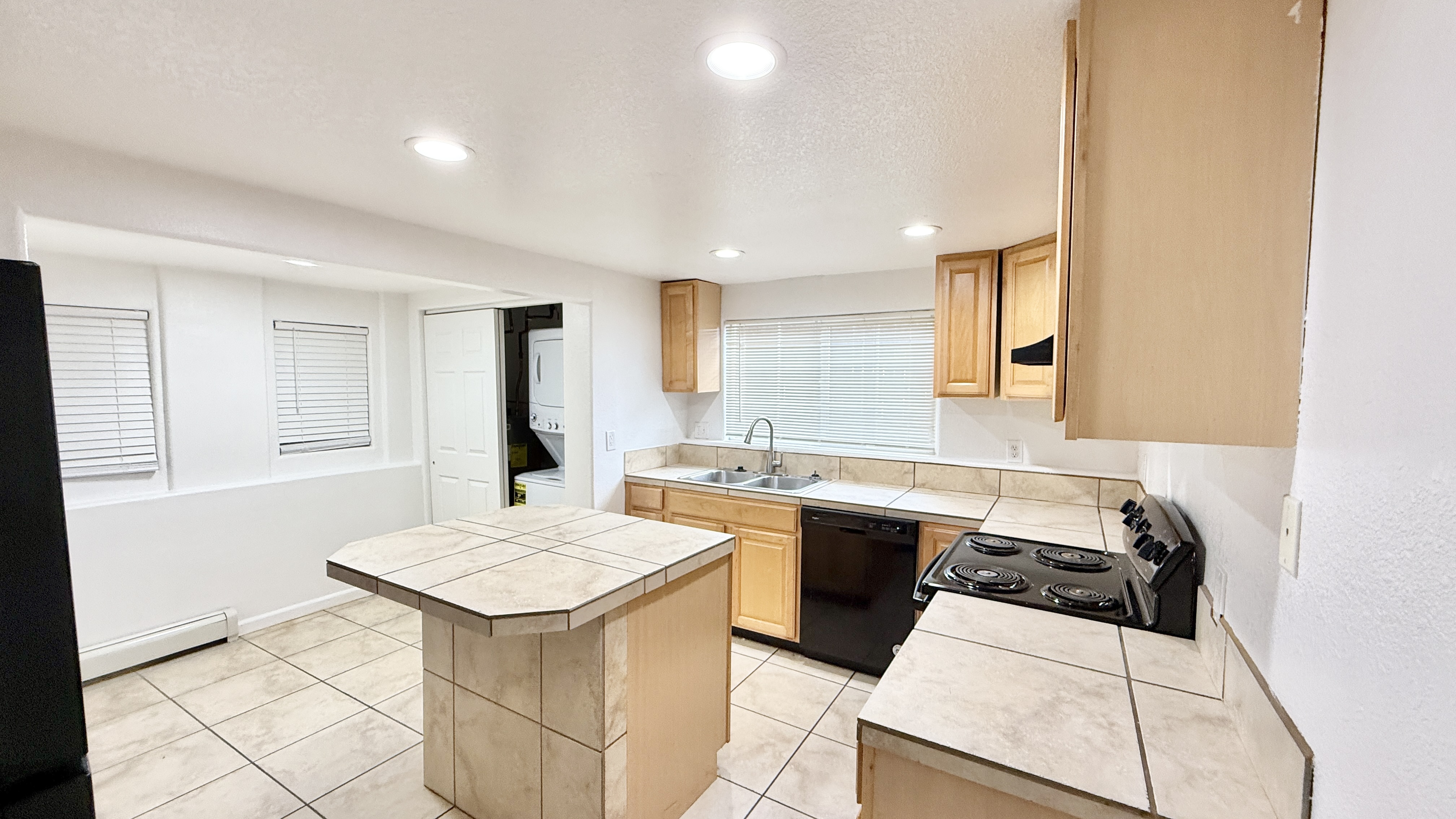Bright and modern kitchen with tiled countertops, wooden cabinets, and built-in appliances.