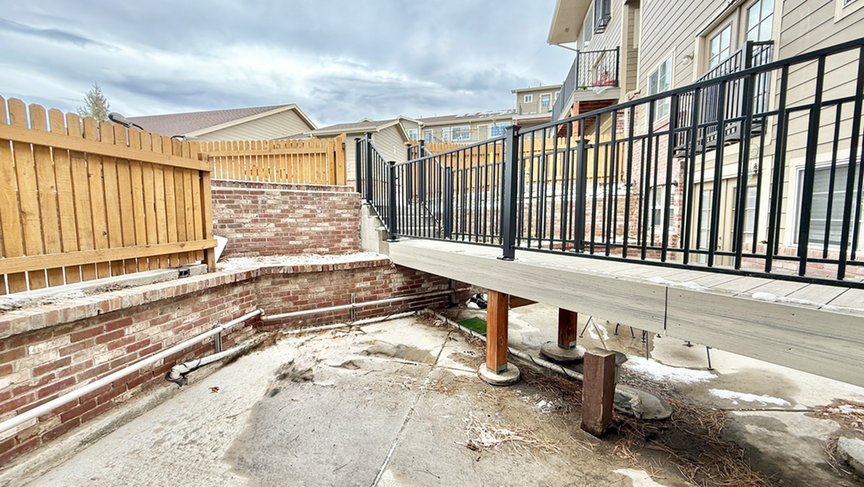 Charming raised walkway and fenced courtyard with brick accents, perfect for relaxing outdoors.