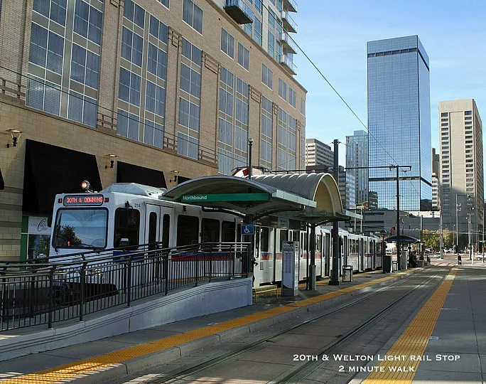 Modern light rail stop at 20th and Welton with high-rise buildings in the background.