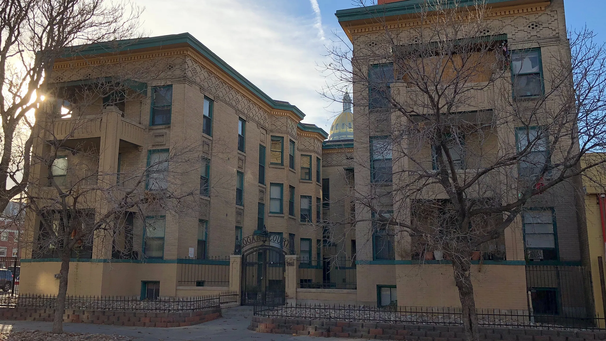 Charming brick apartment building with classic architectural details and mature trees.