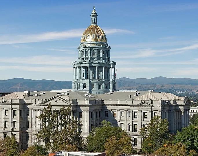 Majestic building with a grand dome set against a backdrop of mountains and blue sky.