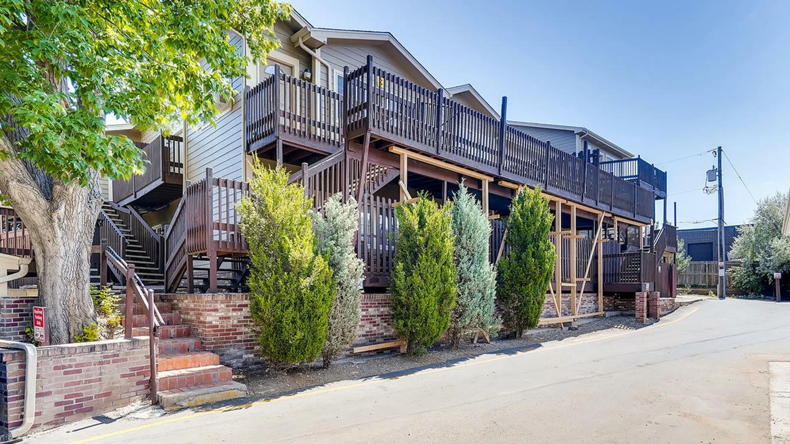 Appealing multi-level apartment complex with wooden stairs and lush greenery.