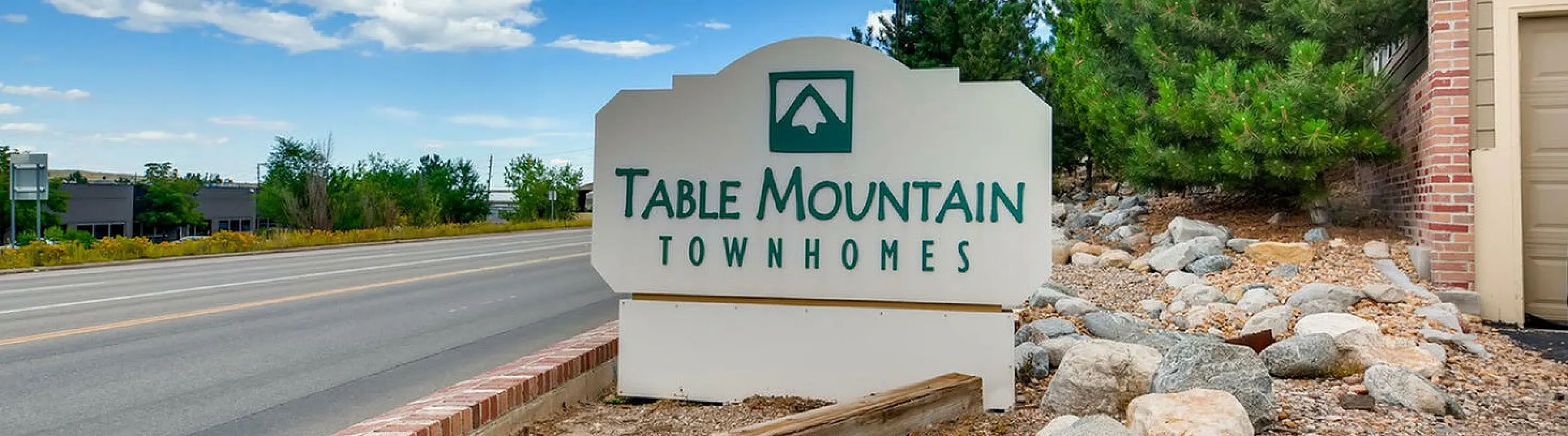 Welcoming entrance sign for Table Mountain Townhomes surrounded by natural landscaping.
