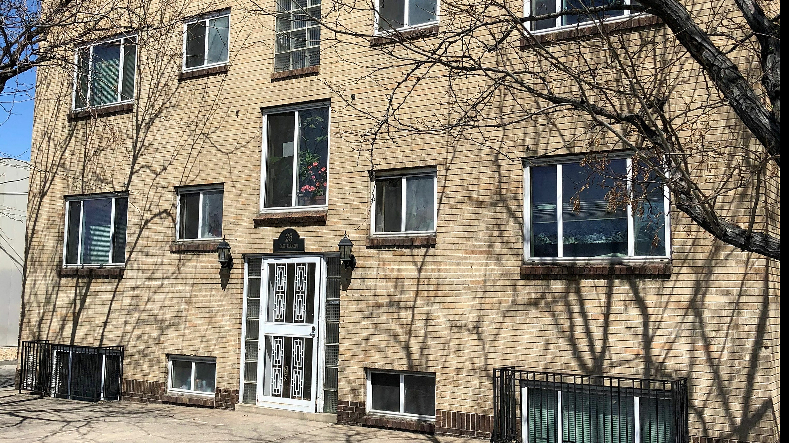 Elegant three-story brick apartment building with large windows and decorative front entrance.