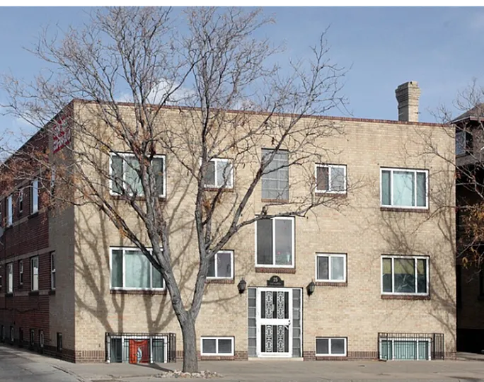 Exterior view of a charming brick apartment building with multiple windows, located on a quiet city street.