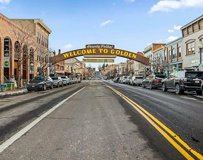 Inviting street view of Golden with a welcoming sign, historic buildings, and parked cars.