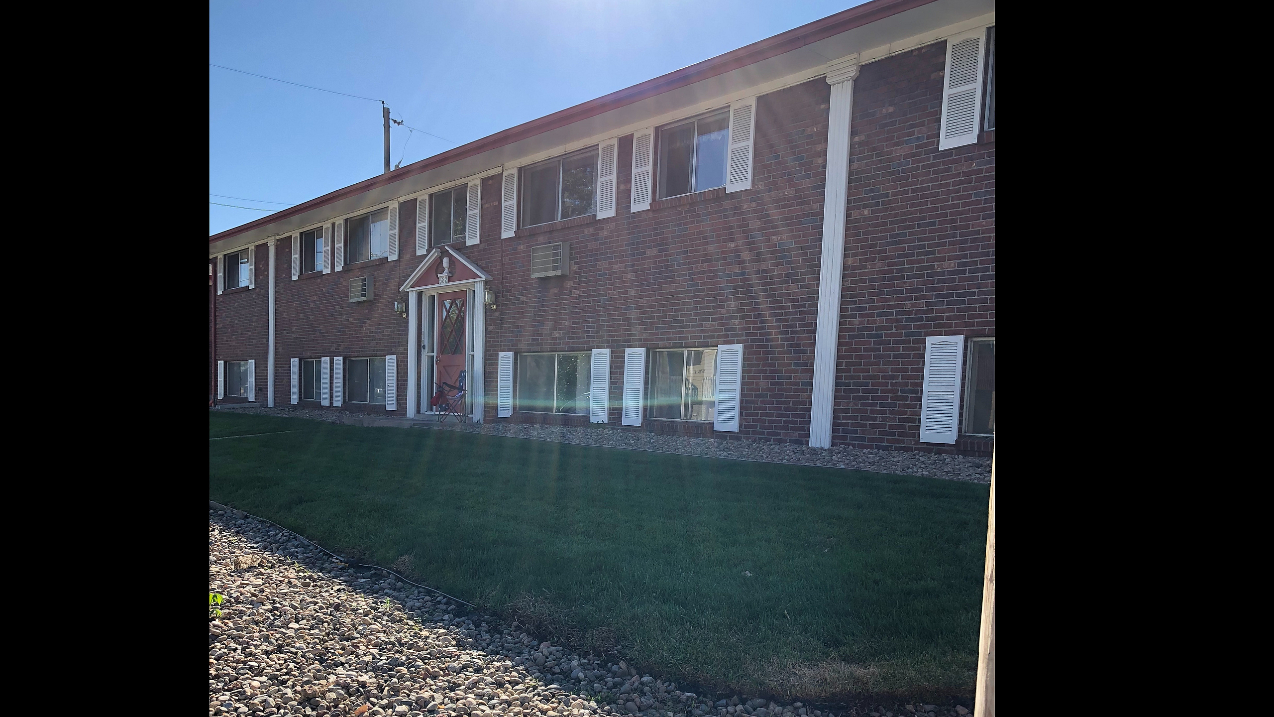 Inviting two-story brick apartment building with a well-maintained lawn and stone pathway.