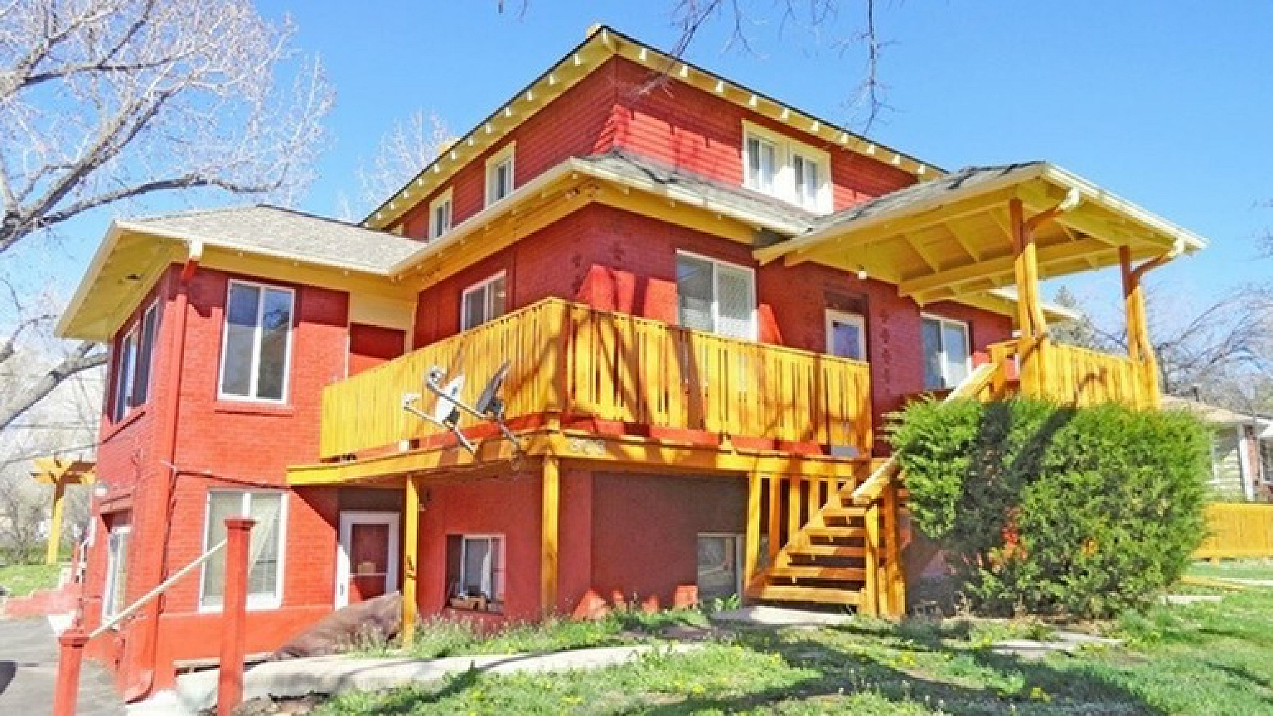 Vibrant red brick house with a spacious wooden deck and well-maintained garden.