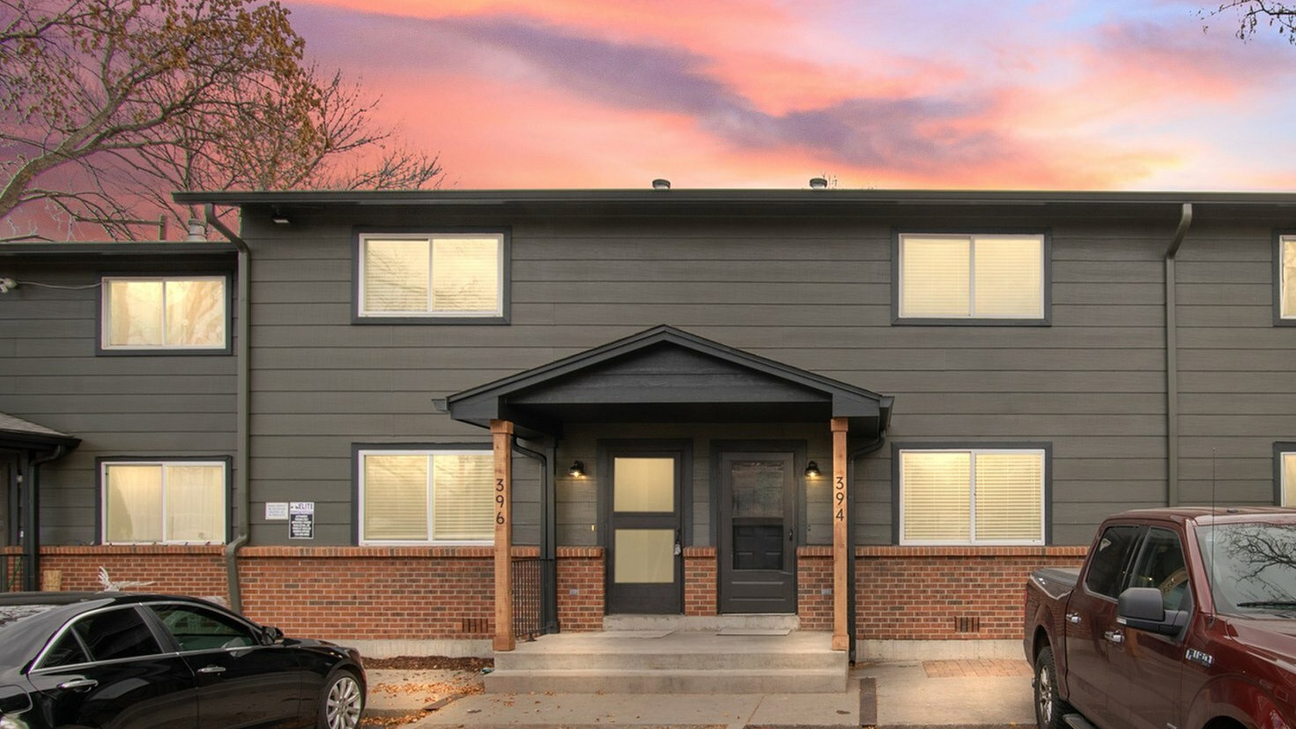 Front view of a modern duplex with a vibrant sunset sky in the background.