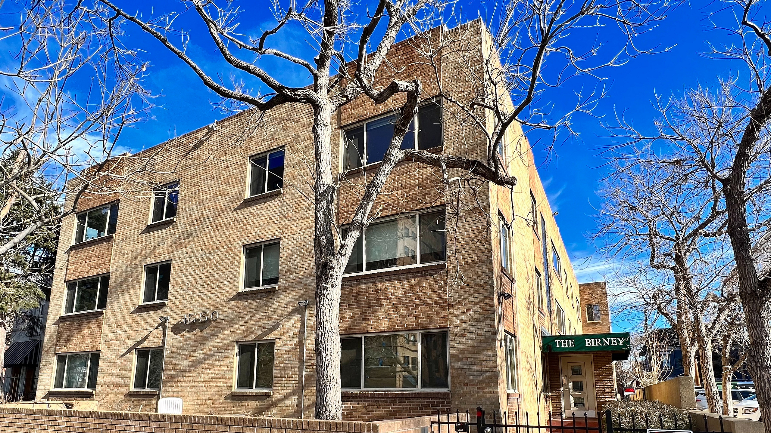 Three-story brick apartment building with classic architecture and gated entrance.