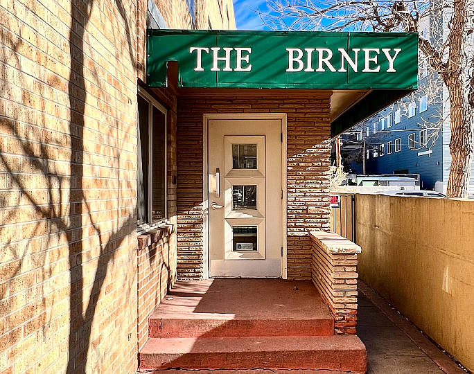 Inviting entrance of The Birney apartment building with a green awning.