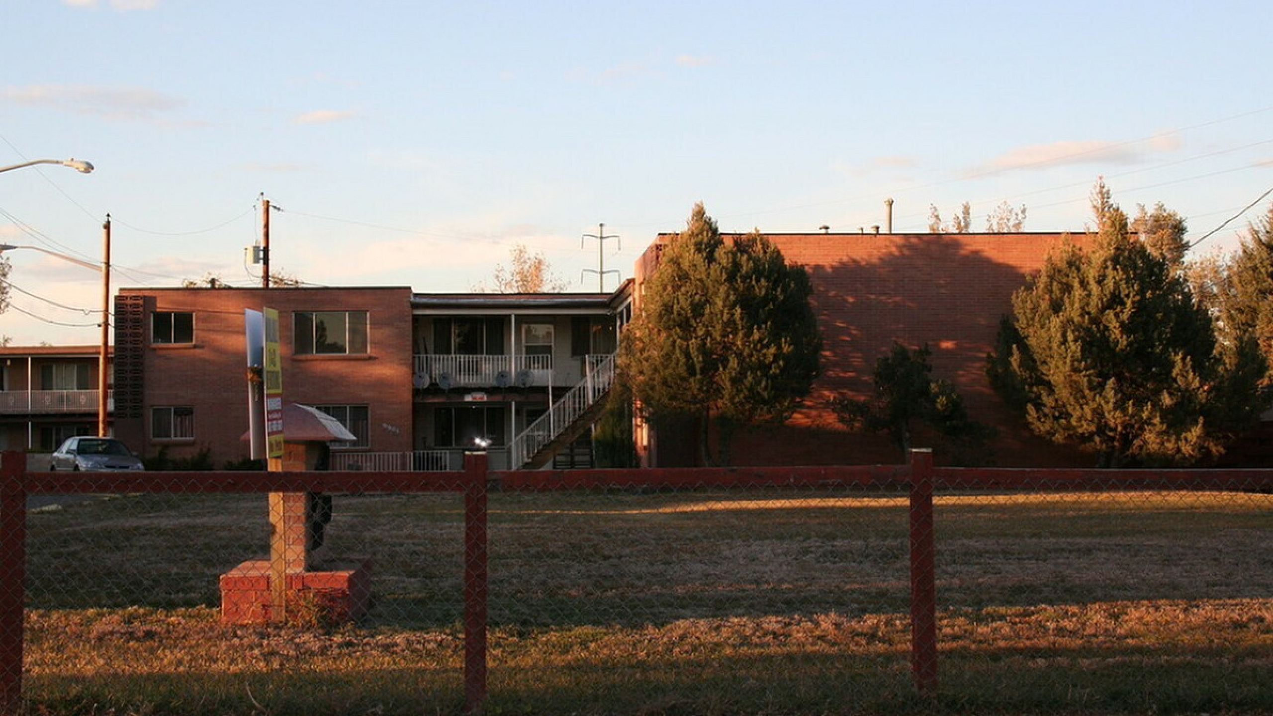 Exterior view of charming brick apartments with greenery set against a beautiful sunset sky.