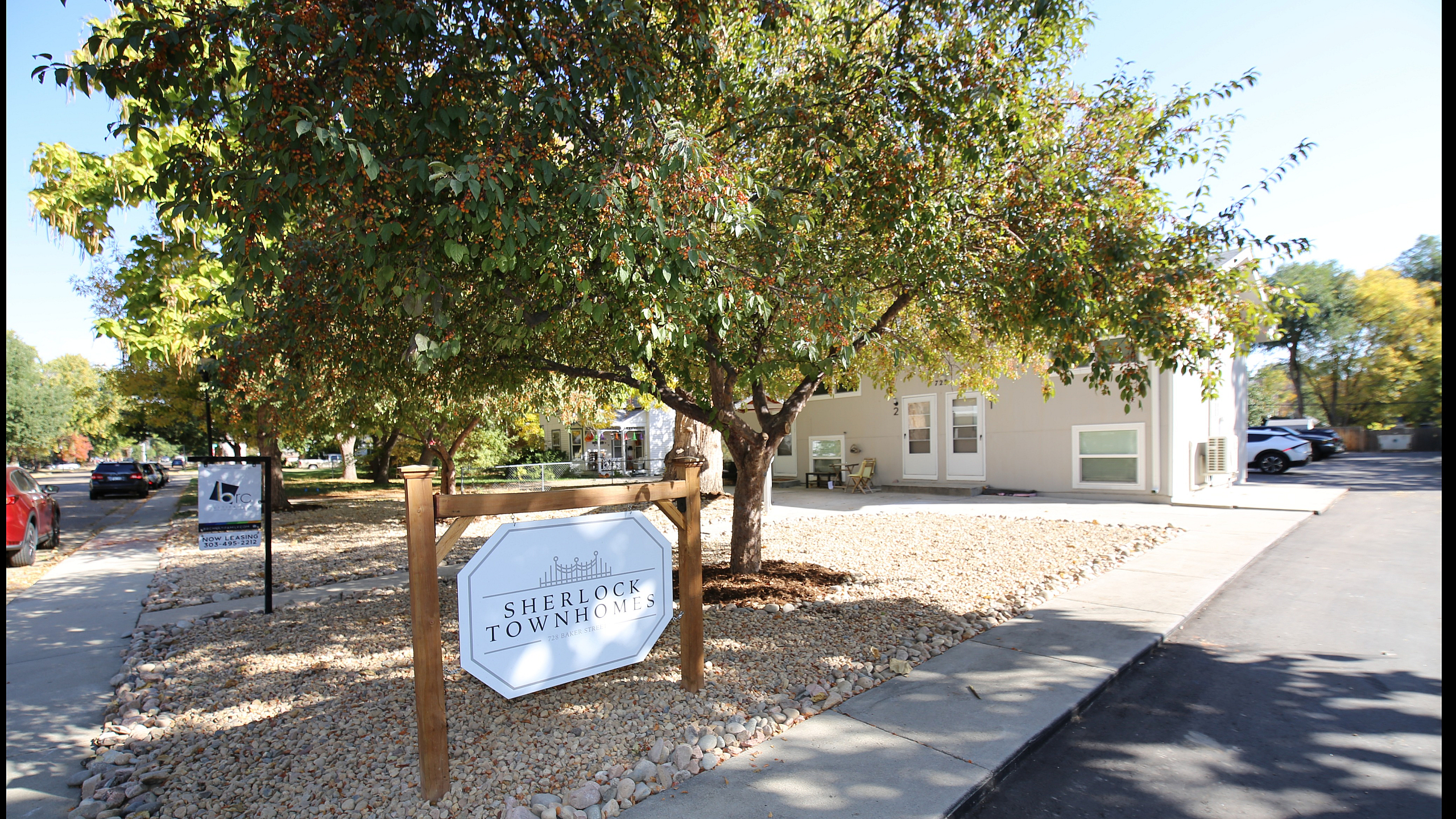 Charming townhome exterior at Sherlock Townhomes, nestled among lush greenery with ample parking.