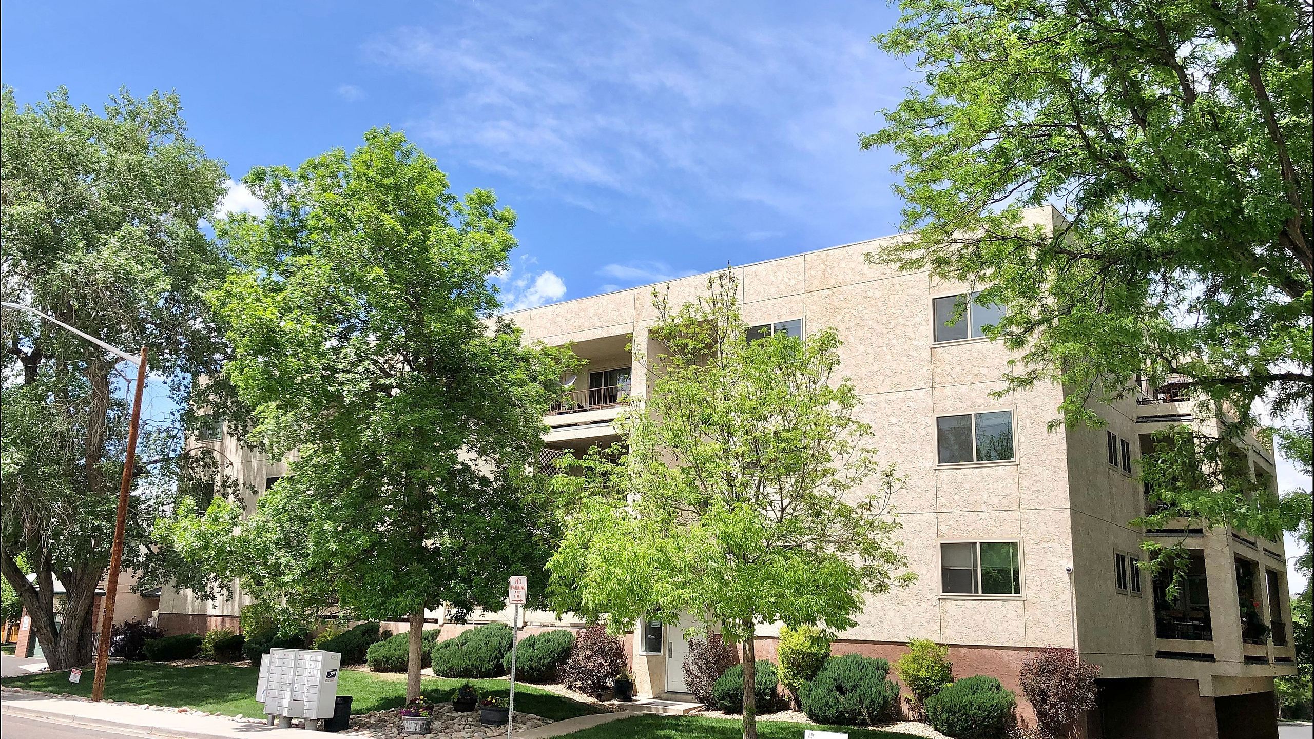 Charming apartment building surrounded by lush greenery, offering a serene and inviting atmosphere on a sunny day.