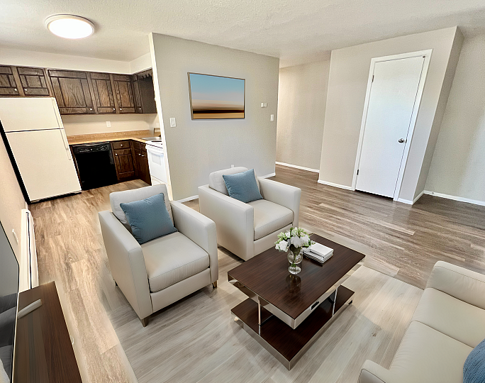 Bright and inviting living space featuring modern furnishings, sleek hardwood floors, and a cozy open kitchen with dark wood cabinets and contemporary appliances.