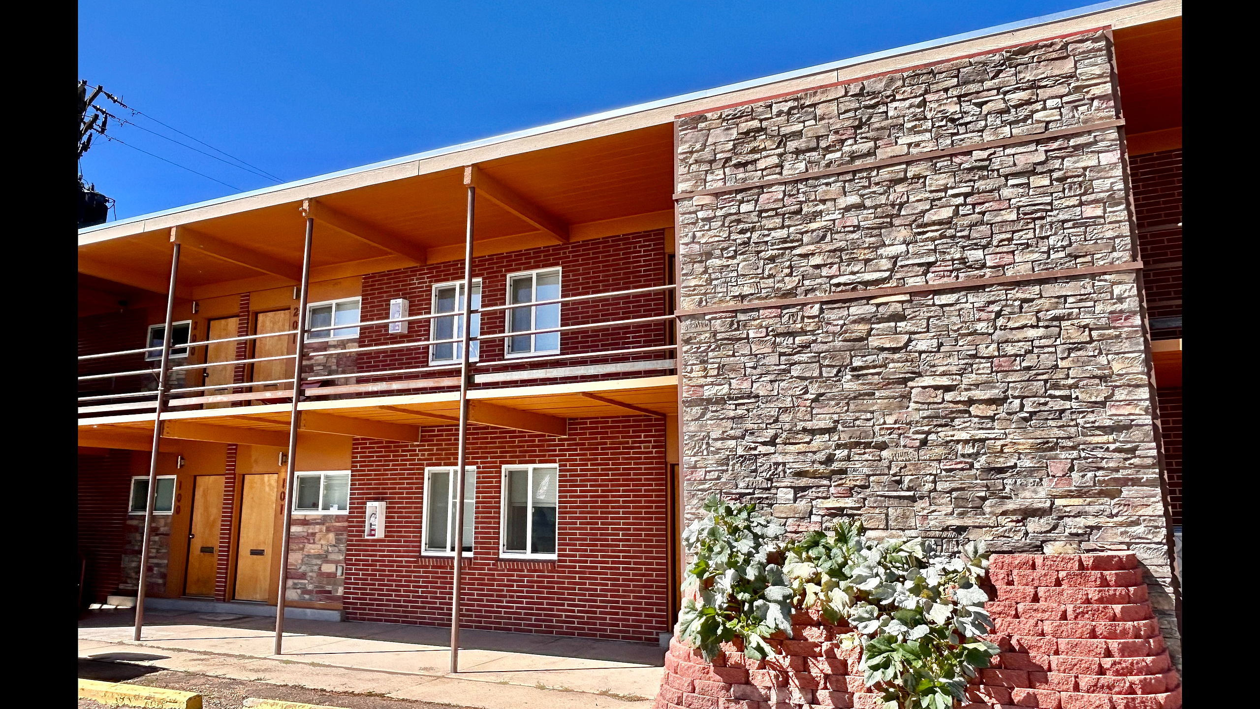 Charming brick apartment building with modern stone accents and lush greenery, capturing a perfect blend of style and comfort.