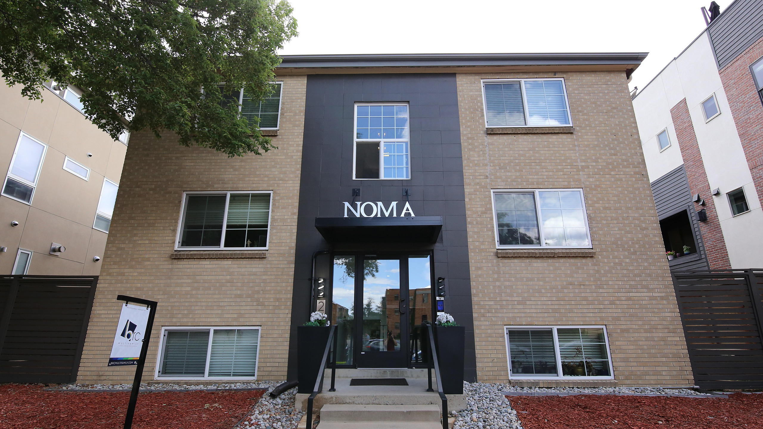 Charming modern apartment building with a stylish brick facade and landscaped entrance at NOMA.