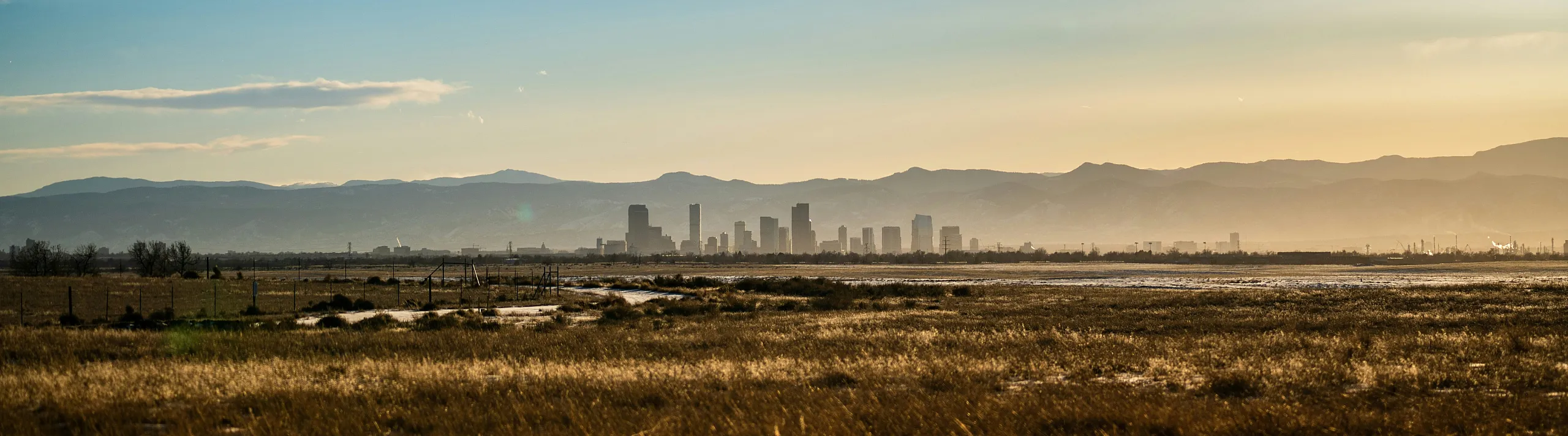 Breathtaking panoramic view of city skyline set against a majestic mountain backdrop during golden hour.