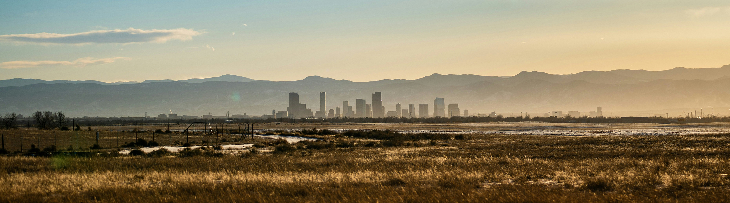 Serene landscape view with distant city skyline and majestic mountains under a vast sky.