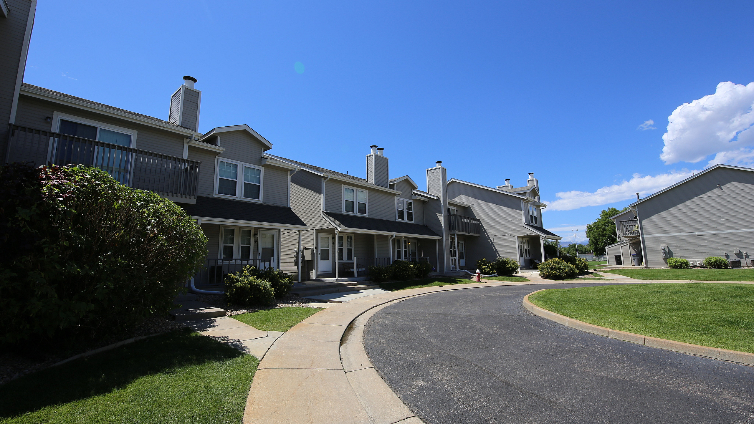Charming townhouse complex with manicured lawns, modern architecture, and a peaceful neighborhood setting.