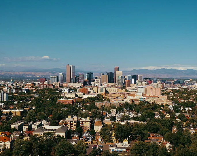 Breathtaking urban skyline with modern skyscrapers and lush greenery set against majestic mountain backdrop.