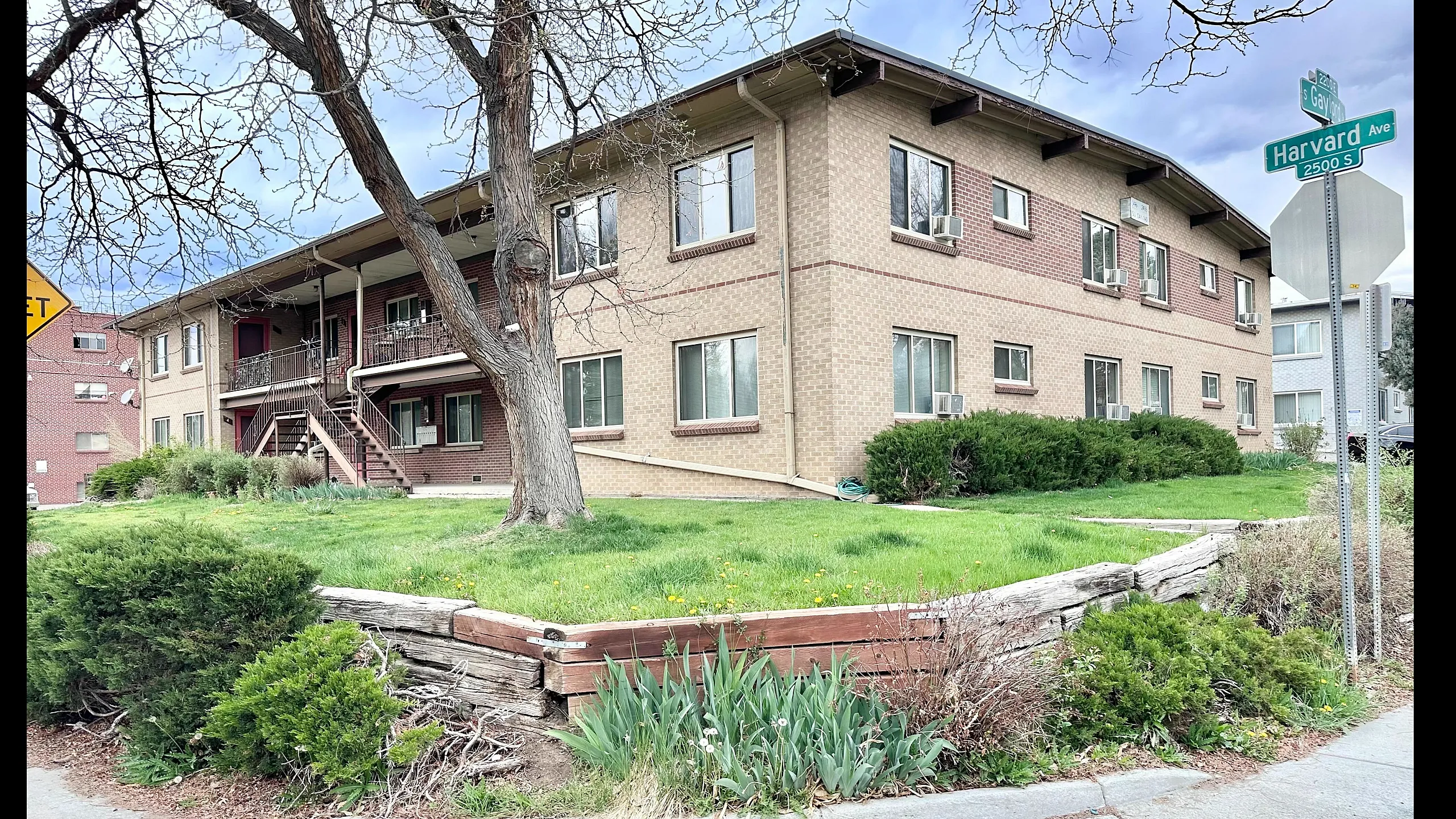 Charming brick apartment building with lush green landscaping at the corner of Harvard Ave and Gay St, offering a serene residential ambiance.