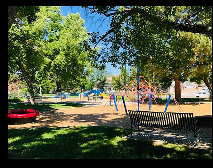 Vibrant community park with lush greenery, colorful playground equipment, and inviting seating areas.