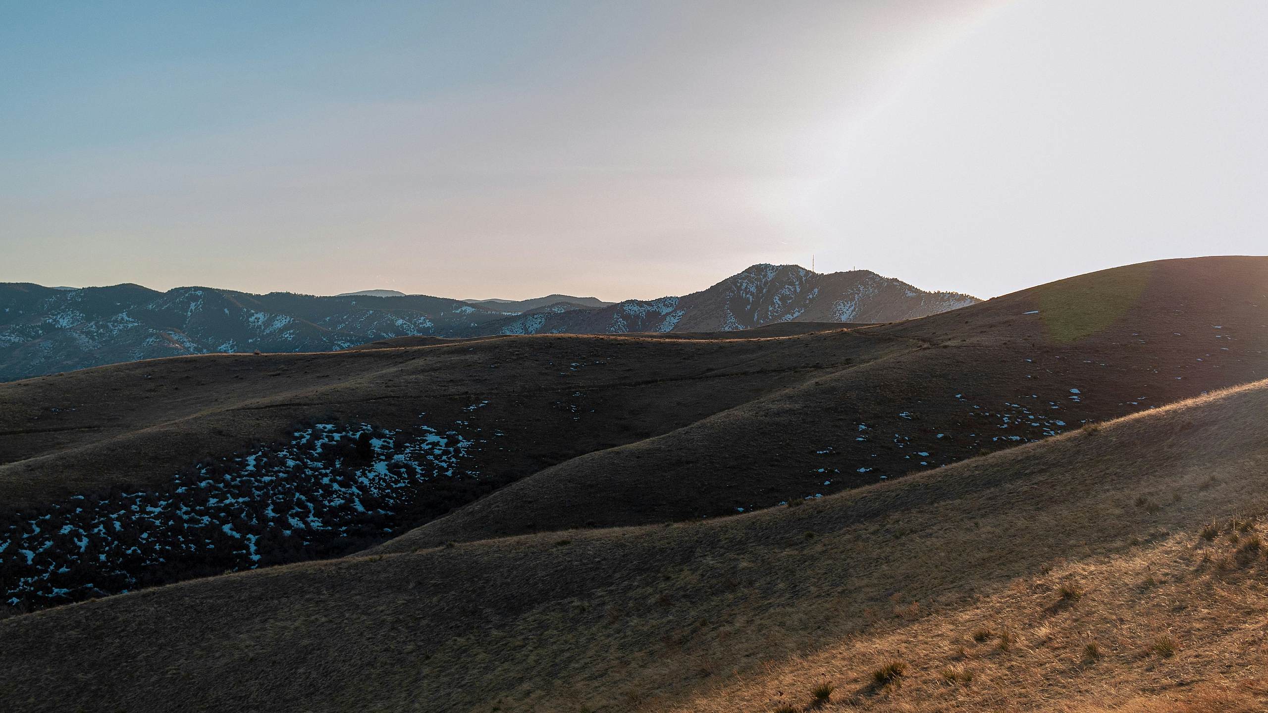 Breathtaking view of rolling hills under a vibrant sunrise, creating a serene natural landscape perfect for a peaceful getaway.