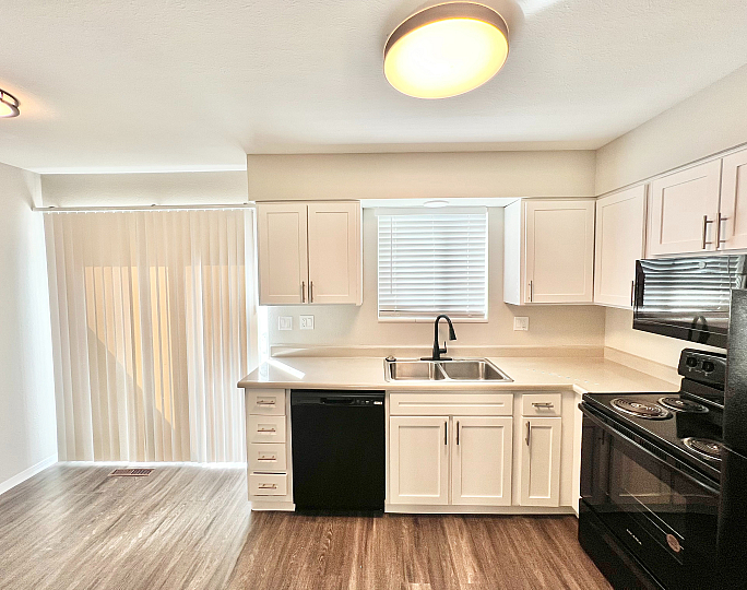 Bright, modern kitchen featuring sleek white cabinetry, black appliances, and an inviting open layout with natural light.