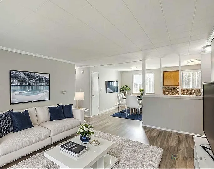 Elegant living room with a plush white sofa, chic decor, and an open dining area, perfect for relaxation and entertaining.