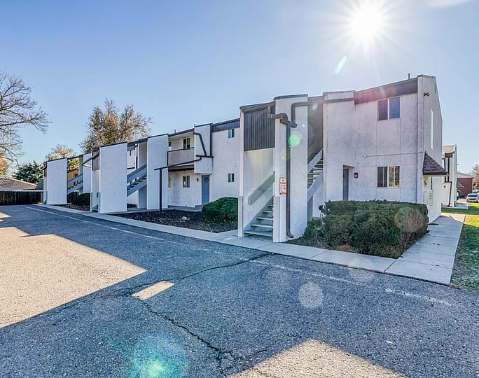 Contemporary apartment complex bathed in sunlight, featuring modern architecture and lush greenery, offering a welcoming atmosphere.