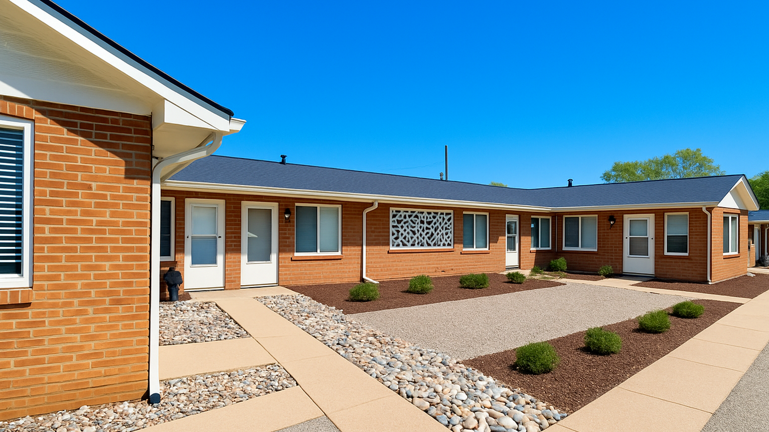 Charming brick apartment complex with modern landscaping and inviting entrances under a clear blue sky.