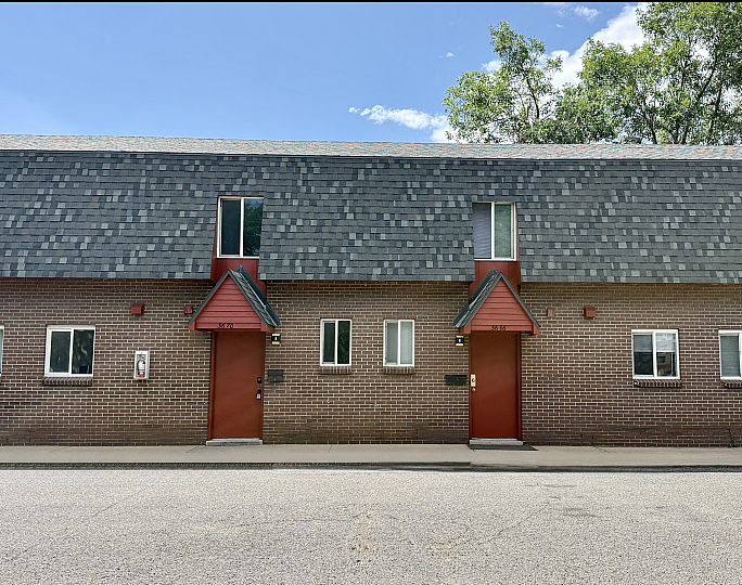 Charming brick townhouses with unique architectural design and contrasting red doors under a clear blue sky.