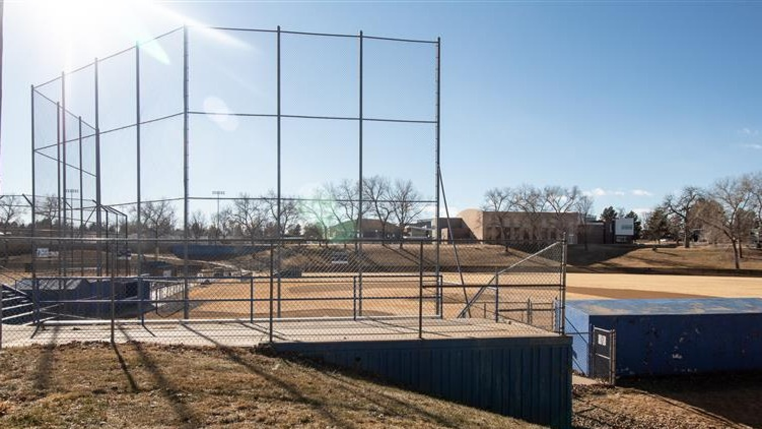 Sunny baseball field with well-maintained grass and bleachers, perfect for outdoor sports enthusiasts.