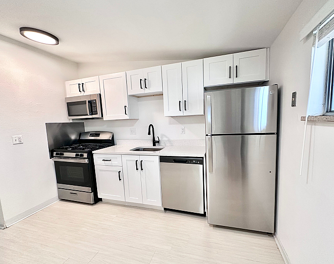 Modern kitchen with sleek stainless steel appliances, white cabinetry, and ample natural light.