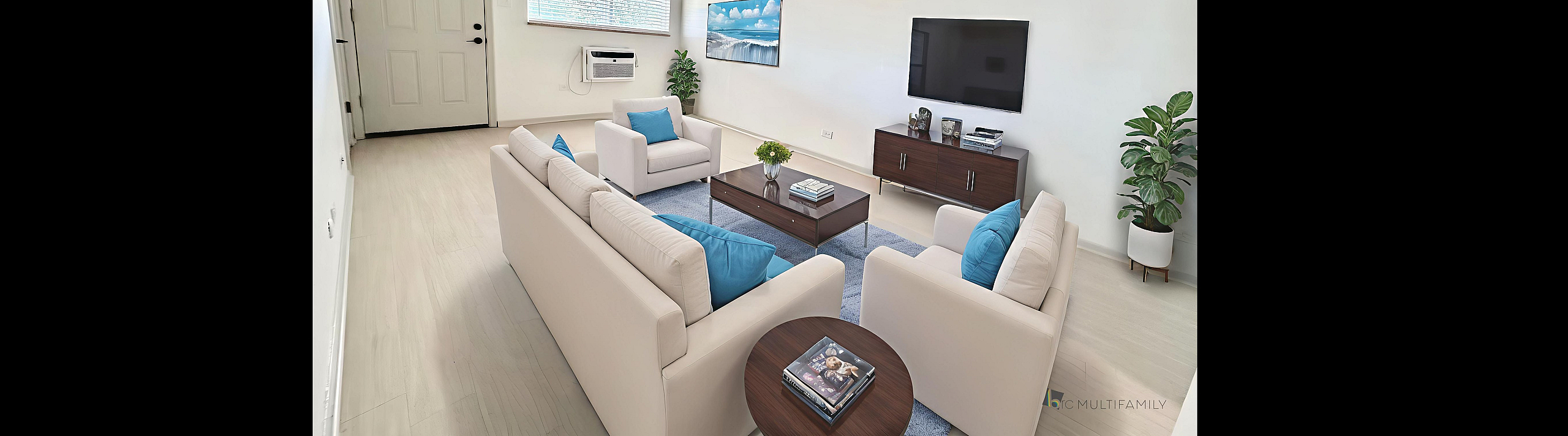 Bright and modern living room with sleek white furnishings, vibrant blue accents, a large wall-mounted TV, and lush greenery.