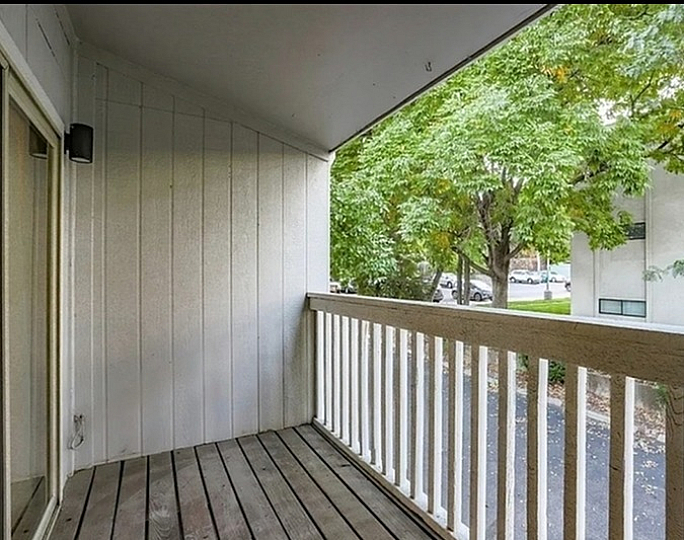 Inviting balcony with wooden decking, surrounded by lush greenery, perfect for relaxation and enjoying nature.
