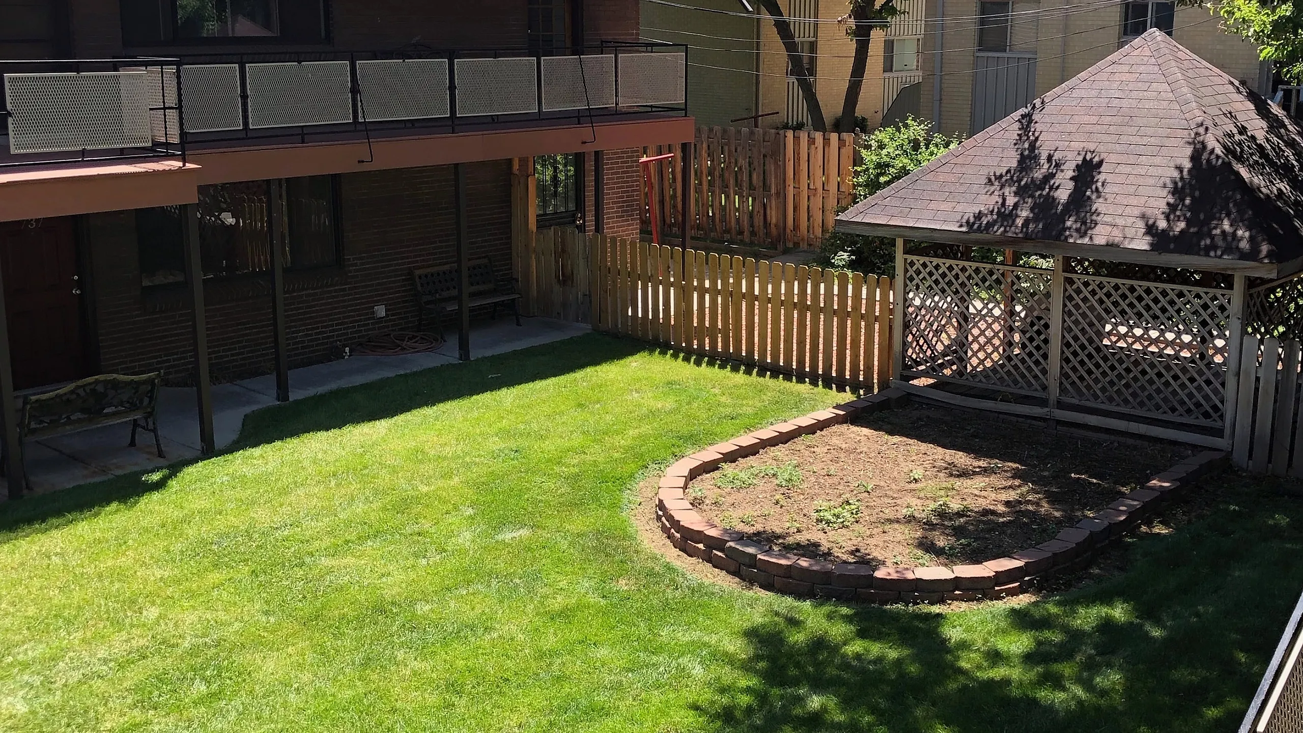 Charming backyard oasis with lush green lawn, shaded patio area, and beautiful wooden fencing, perfect for relaxation and outdoor gatherings.